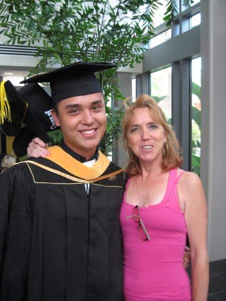 Christine stands next to her son who is wearing a graduation gown