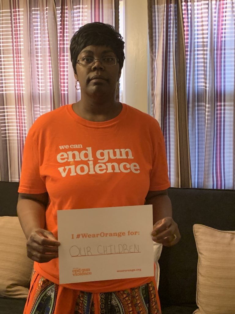 Jenevia Blanks wearing a Wear Orange t-shirt and holding up a sign that says “I #WearOrange for our children”