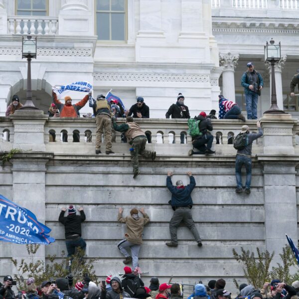 Supporters of President Donald Trump climb the west wall of the the U.S. Capitol