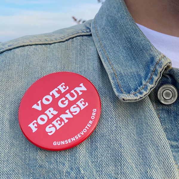 Featured image for the Gun Sense Voter Guide. A person wears a faded light-blue denim jacket and a white t-shirt. A red 