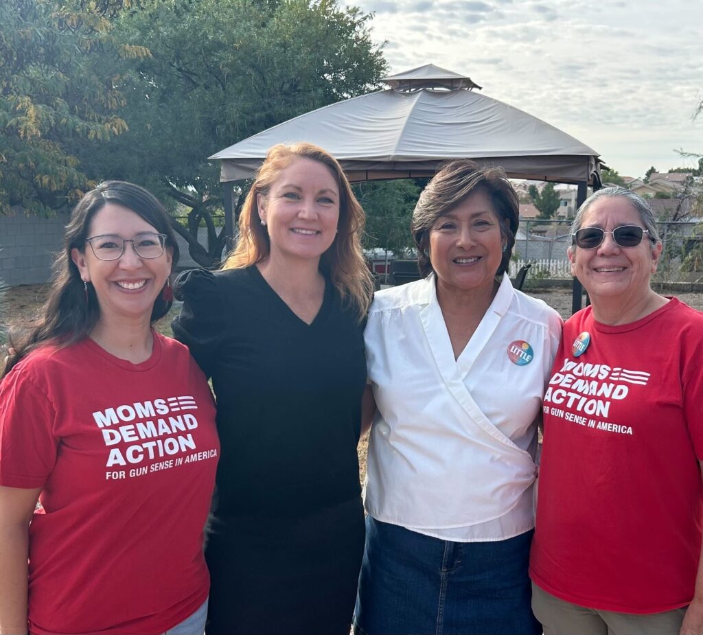 A mom and daughter take a photo with Gun Sense Candidates in New Mexico. The candidates stand in the middle; the mom and daughter bookend them and are wearing red Moms Demand Action t-shirts.