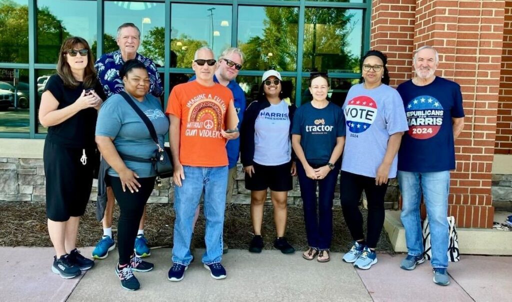 A group of 8 volunteers in North Carolina pose for a photo. The volunteer on the far right wears a navy blue t-shirt with the text "Republicans for Harris 2024".