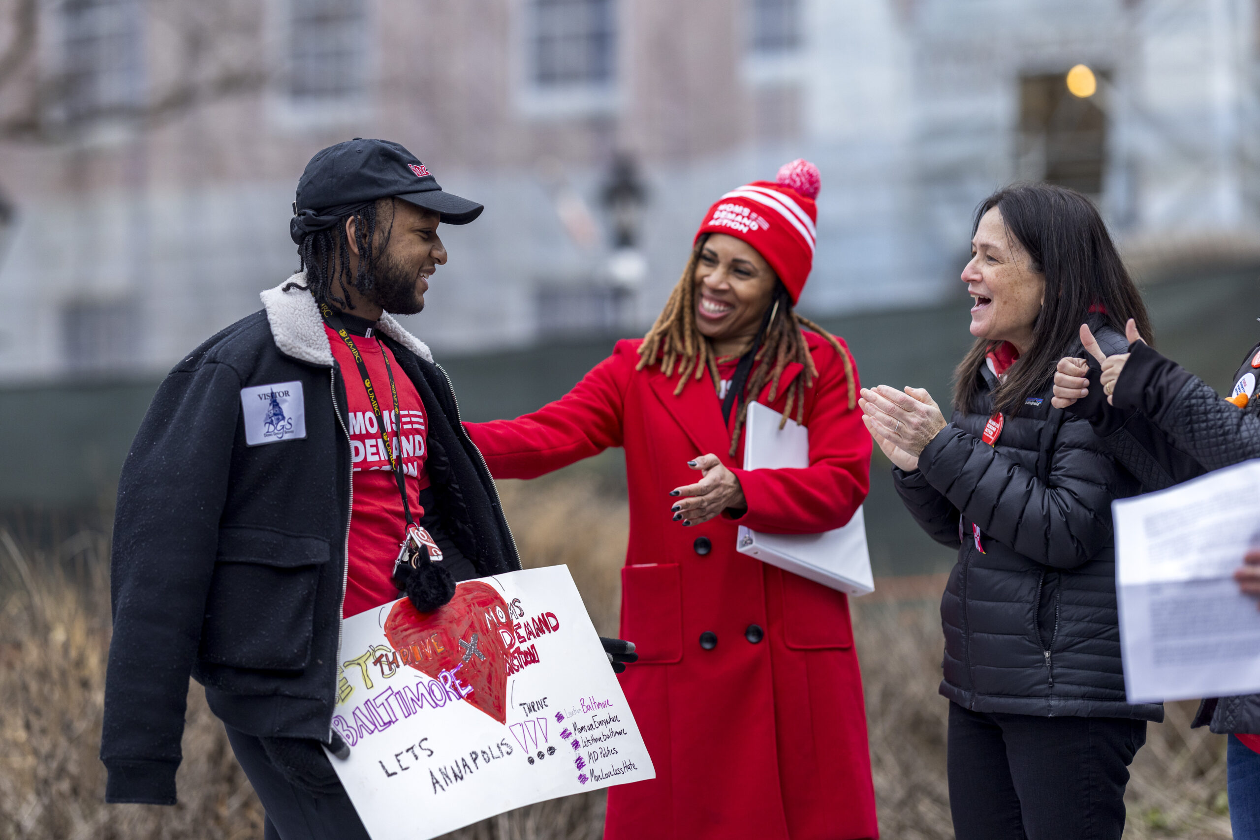 Angela Ferrell-Zabala, executive director of Moms Demand Action, wears a red winter jacket and a Moms Demand Action winter hat. She is smiling and talking to a volunteer wearing a Moms Demand Action t-shirt.