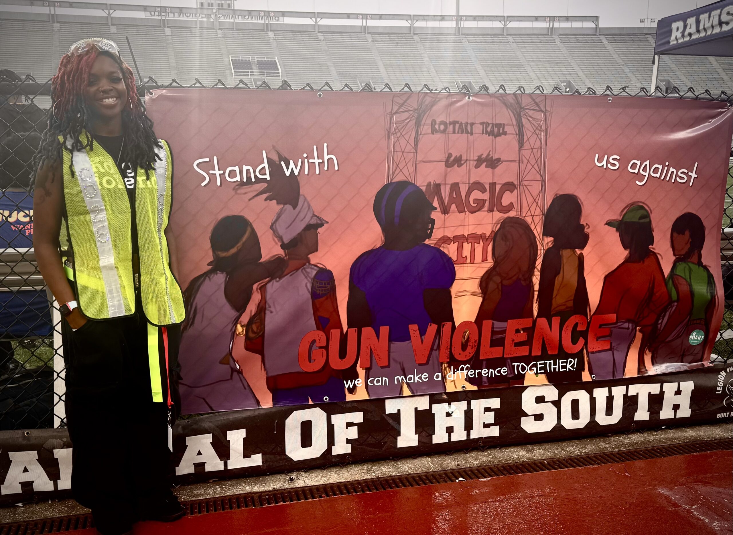 JaCohri Terrell stands next to a gun violence prevention banner she designed for the Stop the Violence Classic.